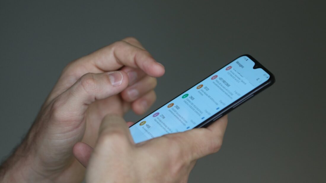 Mãos segurando um celular com a tela acesa