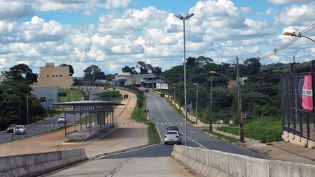 Avenida com corredor exclusivo de ônibus, carros circulando e céu com nuvens em Goiânia