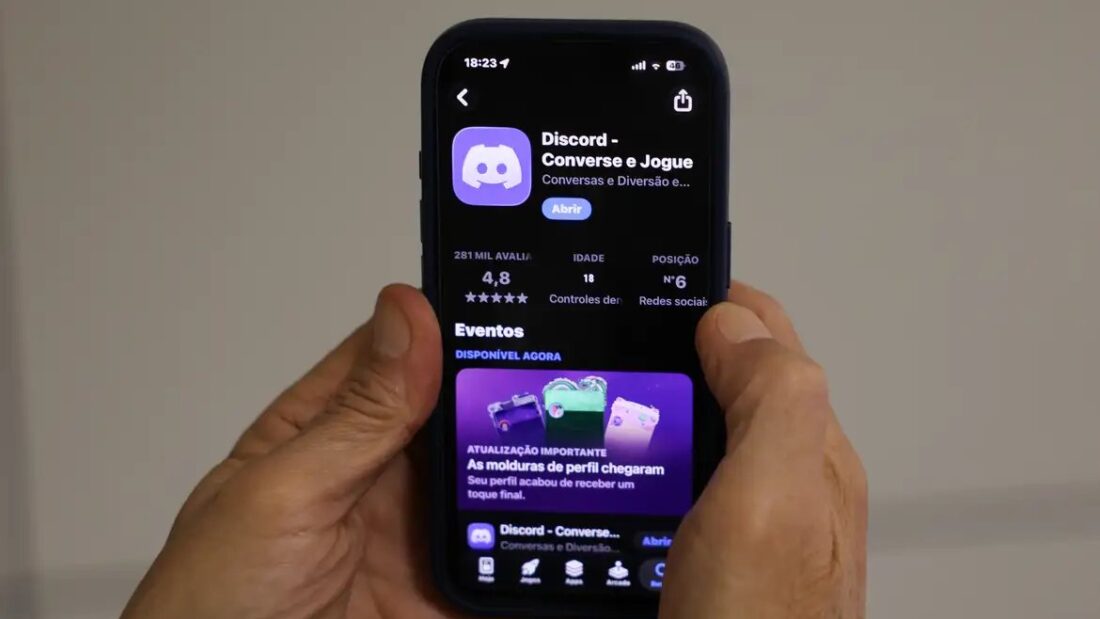 Mãos segurando um celular com a página do aplicativo Discord aberta na loja de aplicativos