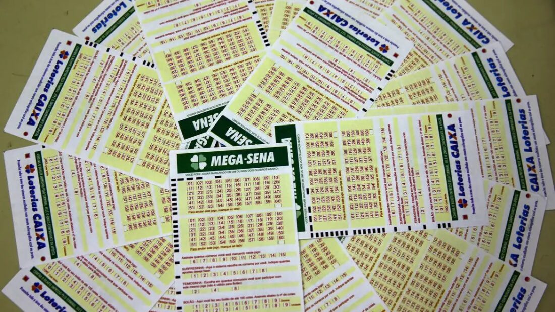 Volantes de apostas da Mega-Sena espalhados sobre uma mesa