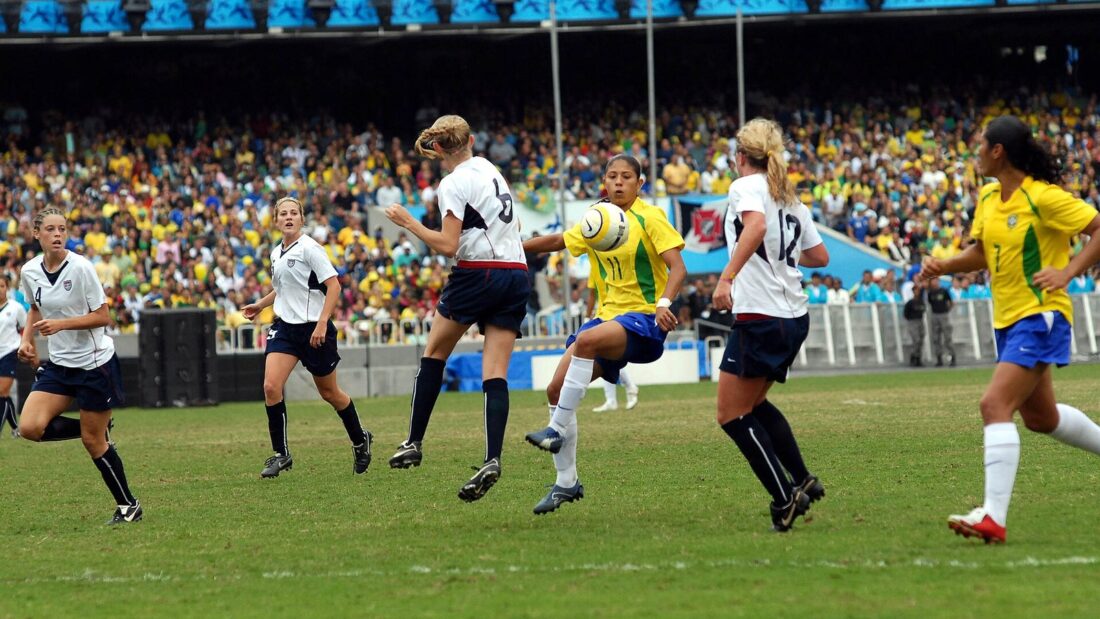 Jogadoras do Brasil, de amarelo, e dos Estados Unidos, de branco, disputam a bola em estádio lotado
