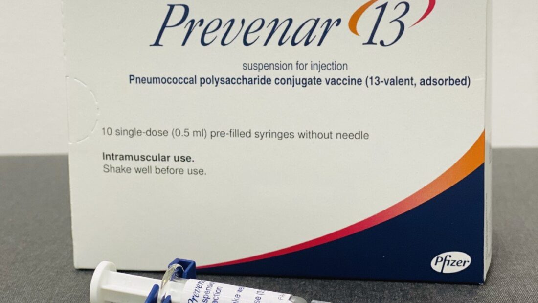 Caixa da vacina pneumocócica conjugada Prevenar 13 ao lado de uma seringa preenchida
