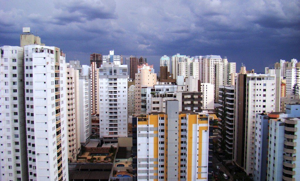 Vista de prédios residenciais altos e brancos no Setor Bueno, em Goiânia, sob céu com nuvens carregadas
