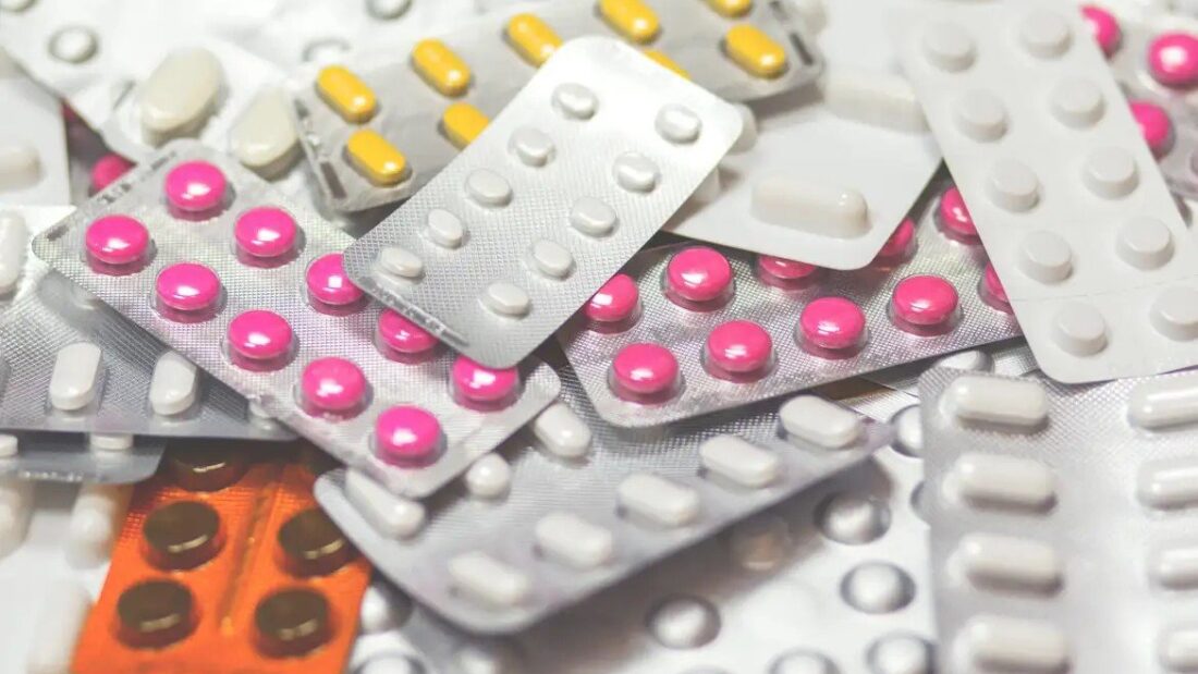 Cartelas de comprimidos de várias cores empilhadas sobre uma mesa