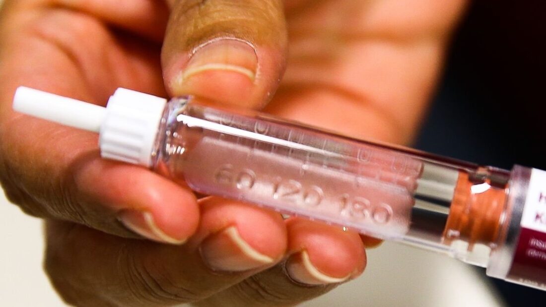 Mão segura uma caneta para aplicação de insulina