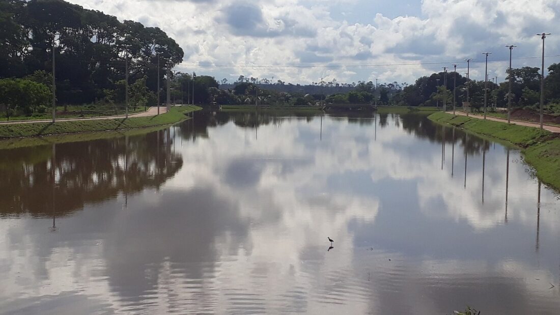 Lago artificial de São Miguel do Araguaia sob céu nublado, com árvores e postes de iluminação nas margens
