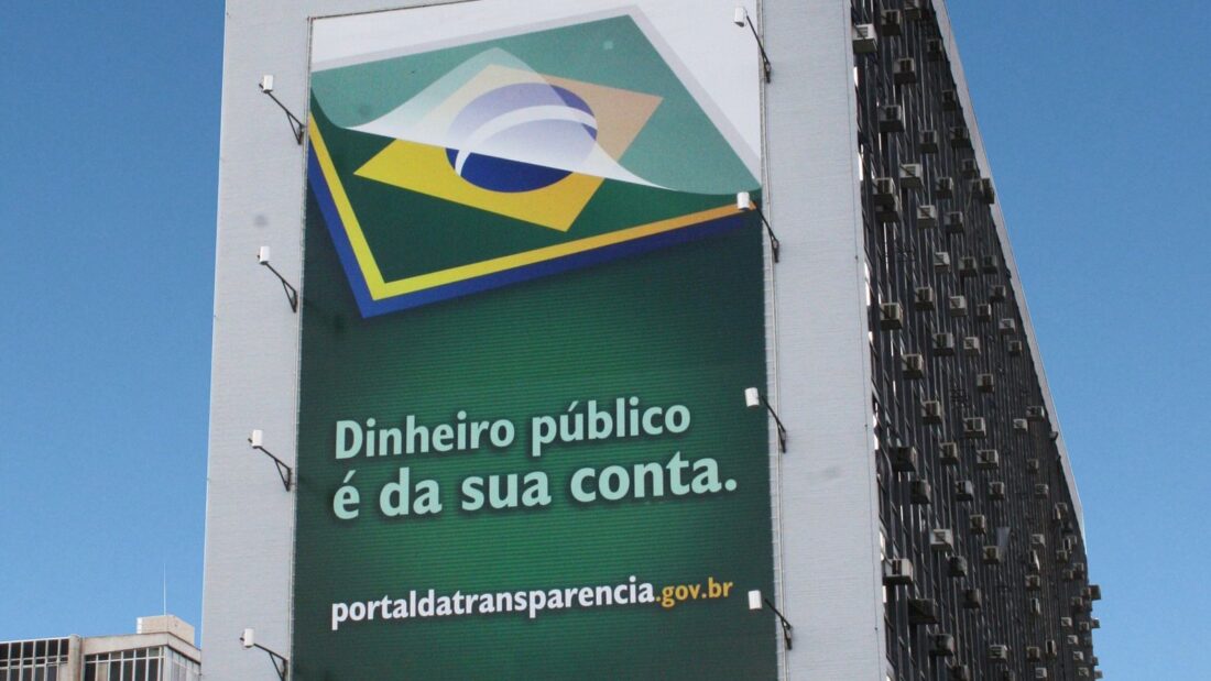 Fachada do Edifício Darcy Ribeiro, sede da Controladoria-Geral da União em Brasília, com o logotipo CGU no alto e um painel com a frase Dinheiro público é da sua conta