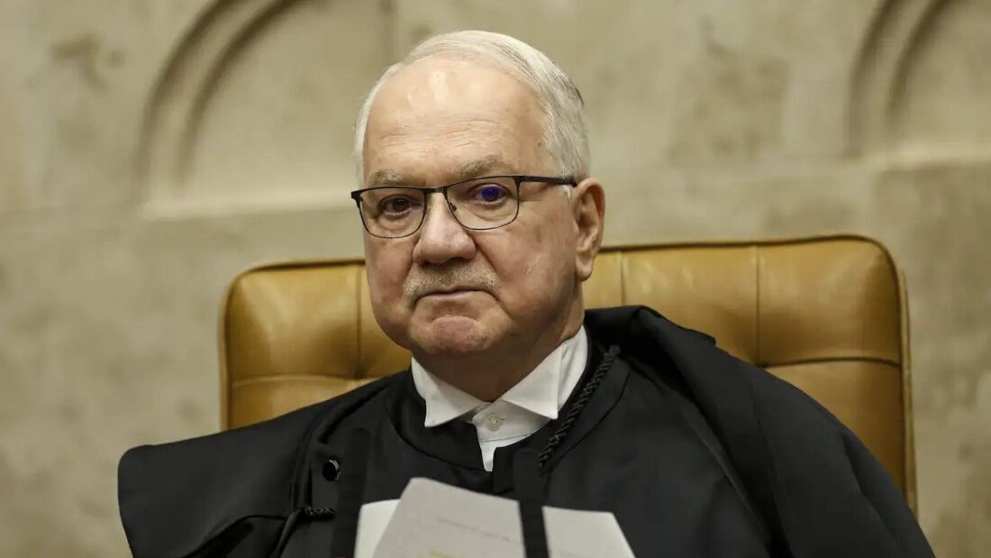 O ministro Edson Fachin, de toga, sentado em cadeira de couro no plenário do Supremo Tribunal Federal, com papéis nas mãos