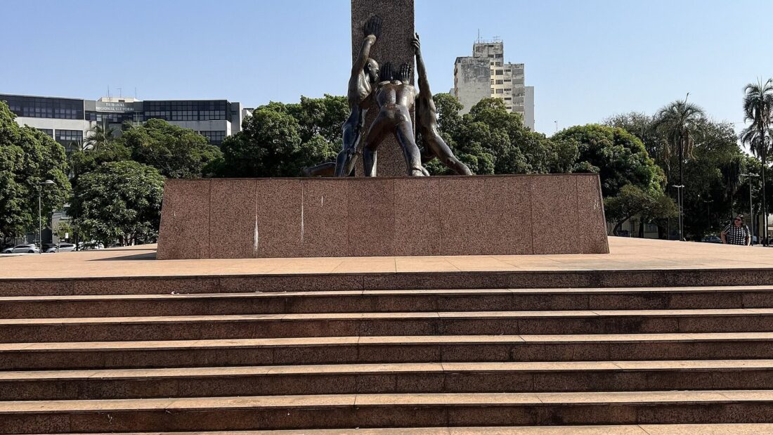 Monumento às Três Raças, escultura de bronze com três figuras humanas segurando um tronco, sobre pedestal escuro na Praça Cívica de Goiânia