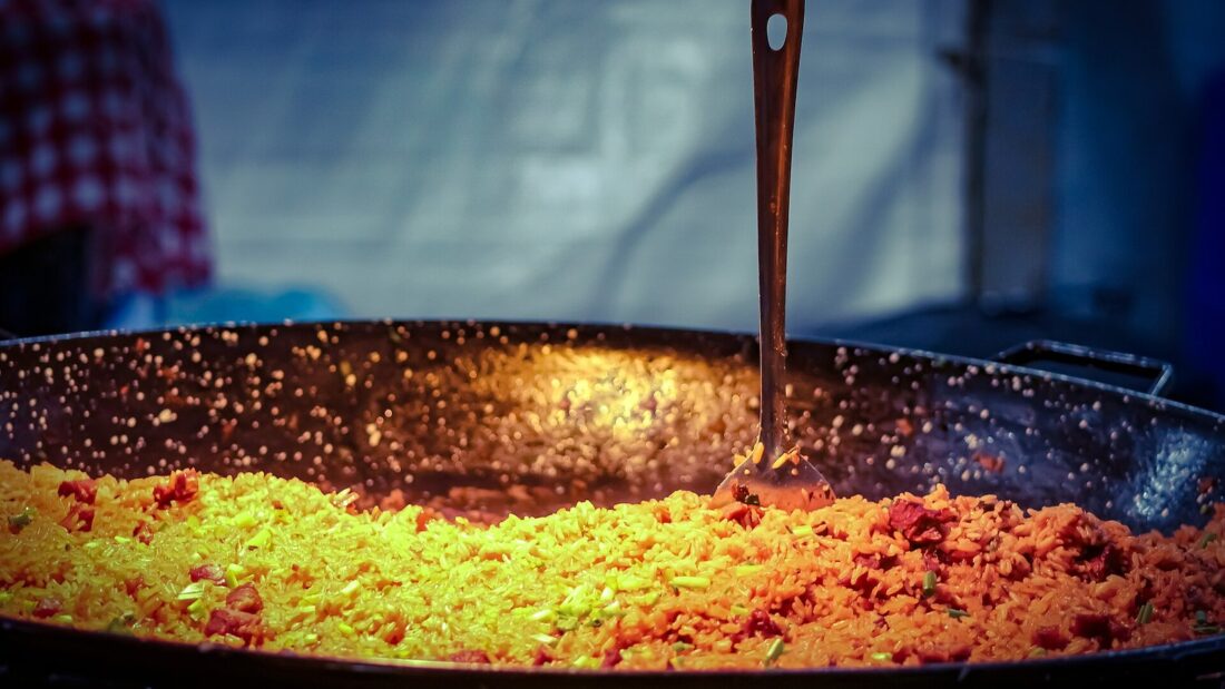 Tacho grande de arroz de carreteiro, com uma concha de cabo longo apoiada na borda
