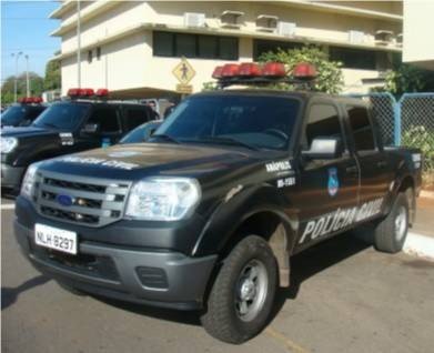 Caminhonete preta da Polícia Civil de Goiás estacionada em frente a um prédio, com outras viaturas ao fundo