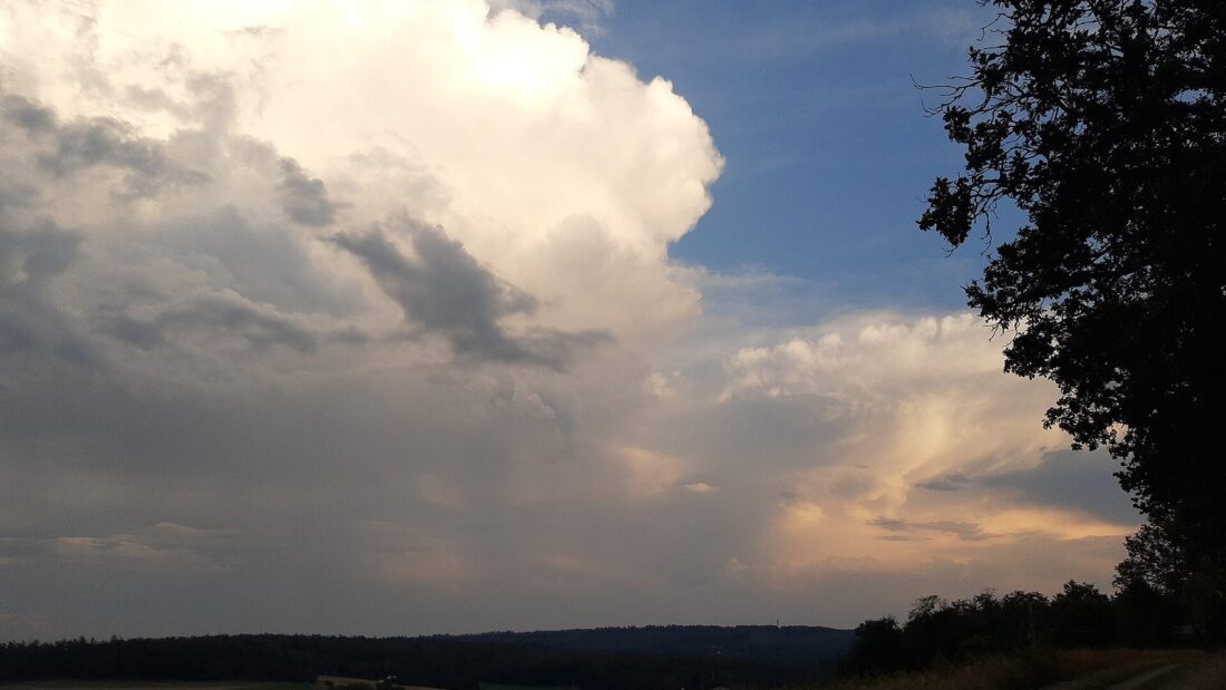 Nuvens carregadas de tempestade sobre campos e estrada rural ao entardecer