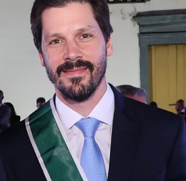 Daniel Vilela, de terno escuro e gravata azul, com uma faixa verde e branca de condecoração no peito