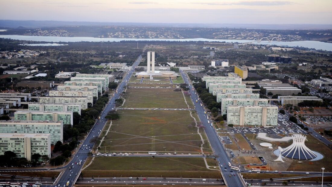 Vista aérea da Esplanada dos Ministérios, em Brasília, com os prédios dos ministérios alinhados dos dois lados do gramado central e o Congresso Nacional ao fundo