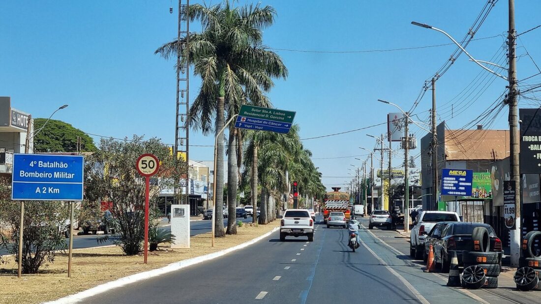 Avenida Presidente Vargas, em Rio Verde, com canteiro central arborizado com palmeiras, carros e placa indicando o 4º Batalhão Bombeiro Militar