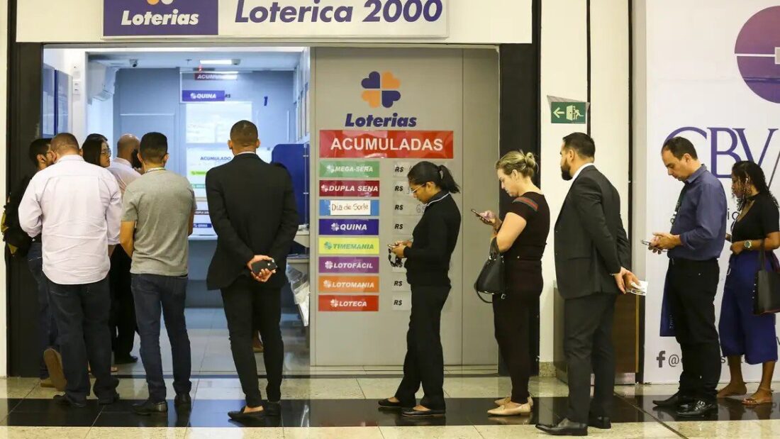Fila de apostadores diante dos guichês de uma casa lotérica
