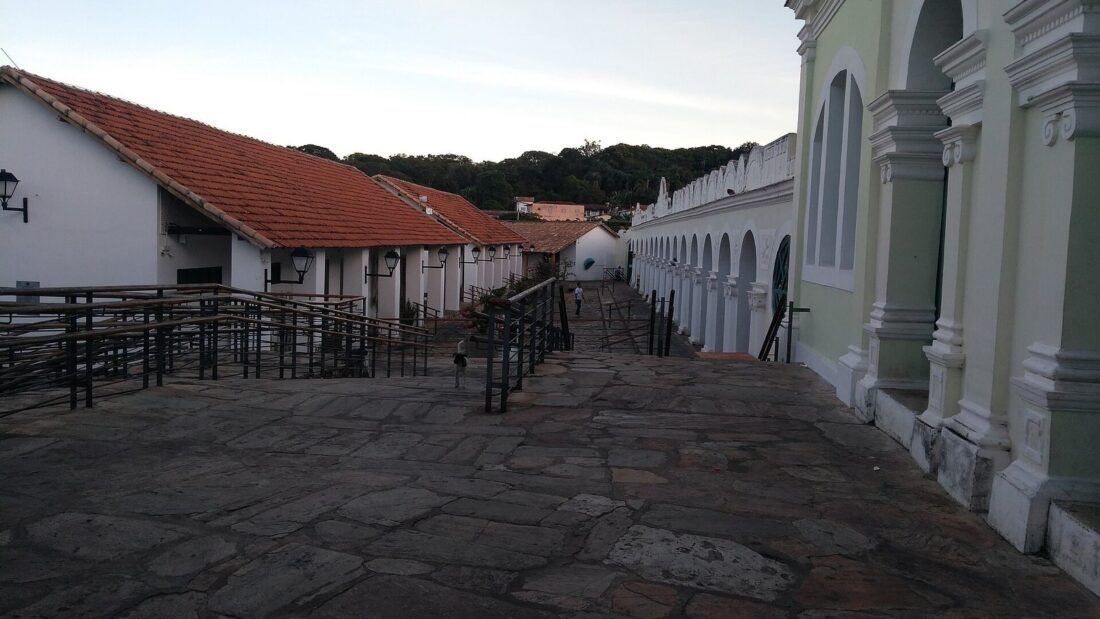Corredor externo de pedra do antigo Mercado Municipal da Cidade de Goiás, com arcos brancos e telhado colonial