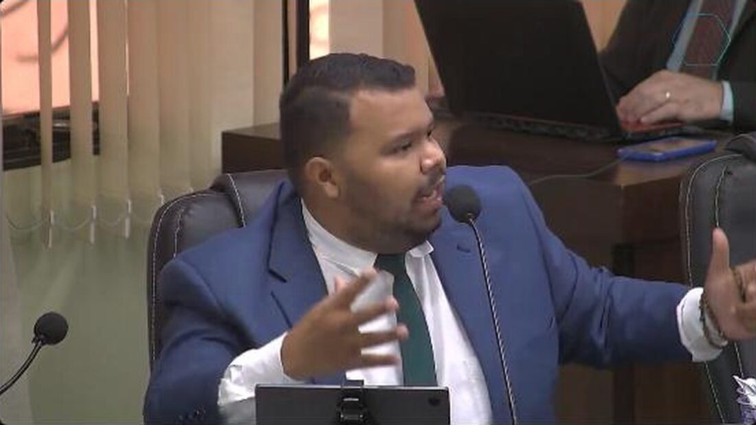 Vereador de terno azul fala ao microfone e gesticula no plenário da Câmara Municipal de Jataí