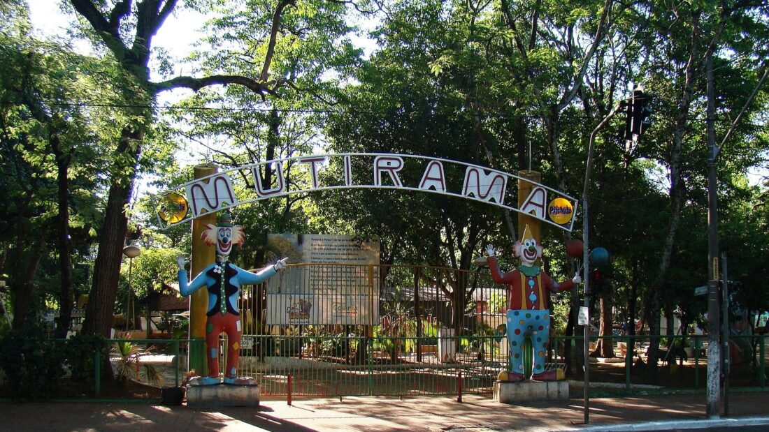 Portal de entrada do Parque Mutirama, com o nome do parque em arco e duas estátuas de palhaços coloridos, cercado de árvores