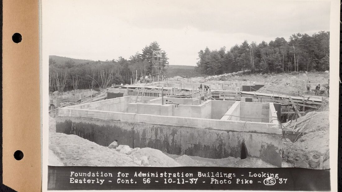 Fotografia antiga em preto e branco de um canteiro de obras com paredes de fundação de concreto recém-construídas dentro de uma escavação
