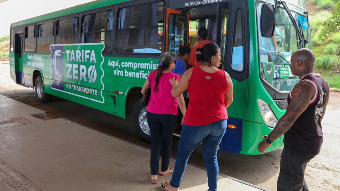 Passageiros embarcam em ônibus verde com a inscrição Tarifa Zero em terminal de Luziânia