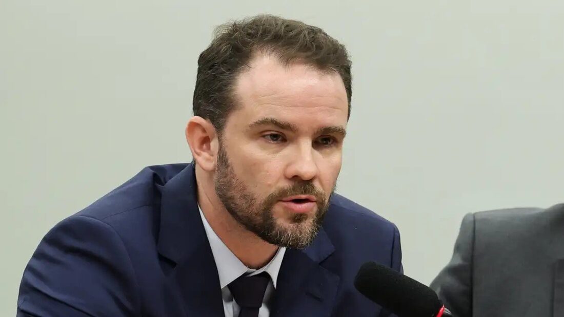 O ministro da Fazenda, Dario Durigan, de terno e gravata, fala ao microfone durante reunião de comissão na Câmara dos Deputados