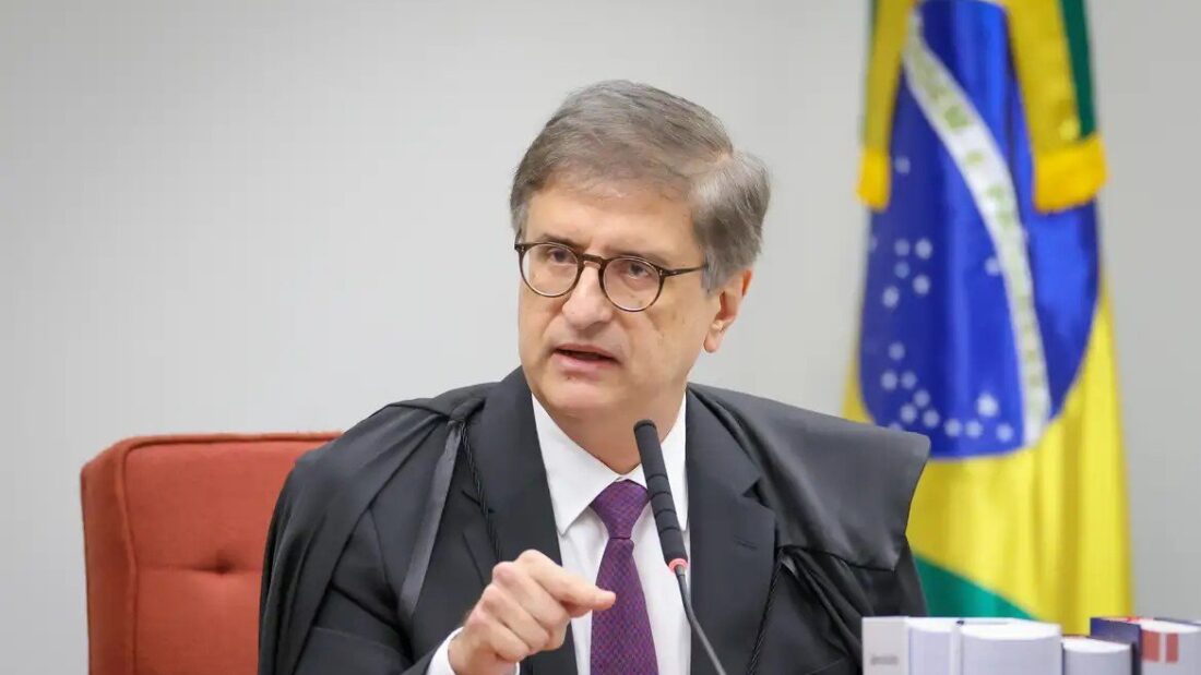 O procurador-geral da República, Paulo Gonet, de óculos e beca, fala ao microfone no plenário do STF, com a bandeira do Brasil ao fundo