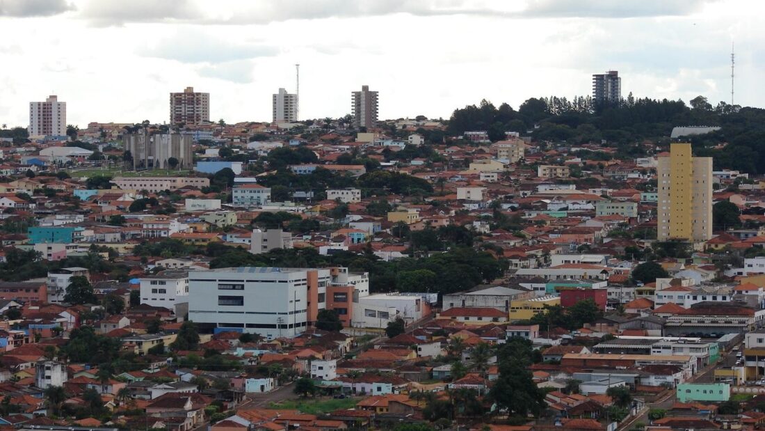 Vista do alto de Jataí, com casas de telhado cerâmico, alguns prédios e muitas árvores entre as quadras, sob céu nublado