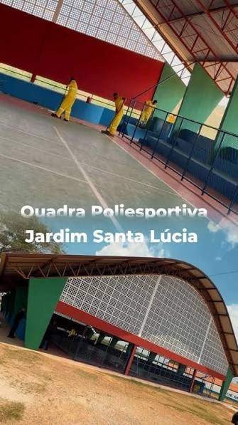 Quadra poliesportiva coberta recém-pintada, com piso cinza, traves e estrutura metálica vermelha, e a inscrição Quadra Poliesportiva Jardim Santa Lúcia