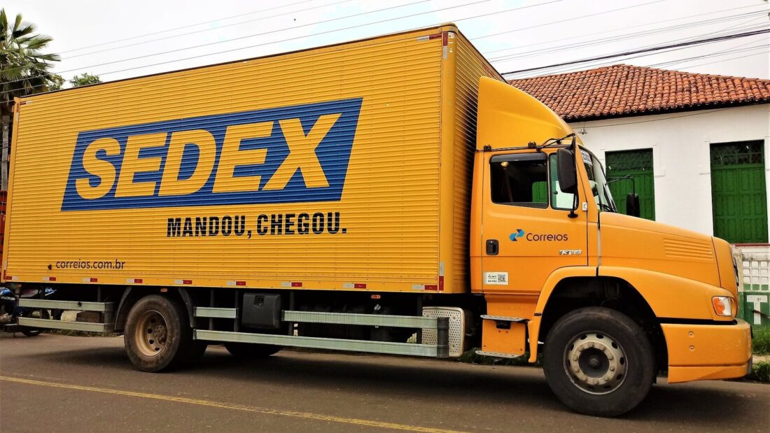Caminhão amarelo com carroceria baú estacionado em uma rua