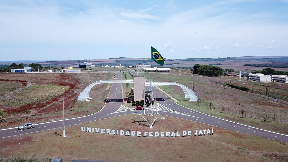 Vista aérea da entrada do câmpus da Universidade Federal de Jataí, com o letreiro com o nome da universidade, um mastro com a bandeira do Brasil e prédios ao fundo