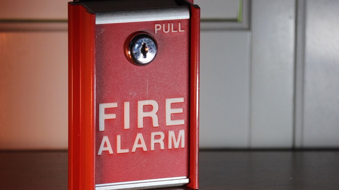 Acionador manual de alarme de incêndio, vermelho, fixado em uma parede