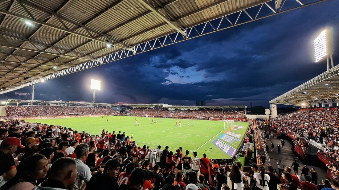 Arquibancadas cheias de torcedores do Atlético-GO no Estádio Antônio Accioly, com o gramado iluminado ao fundo